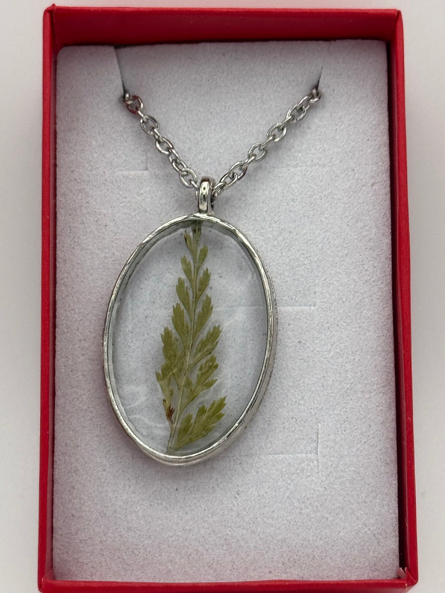 Necklace with flower encased in clear resin on a stainless steel chain