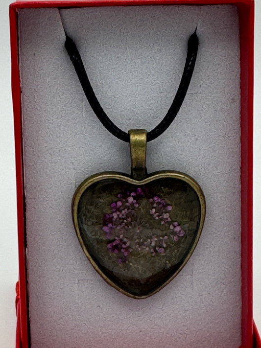 Pink flower contained in clear resin and metal bezel necklace, with black waxed chain