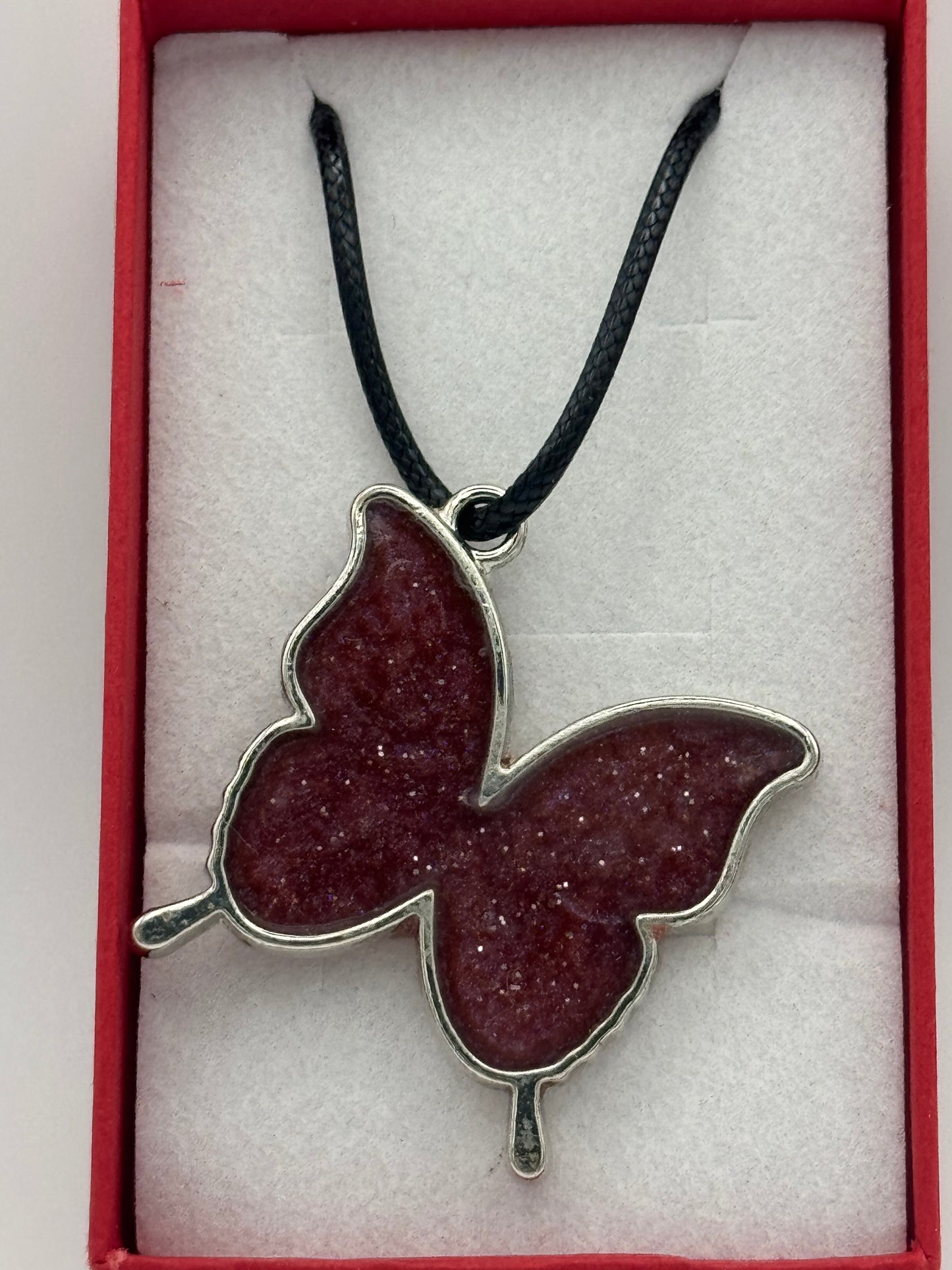 Red resin and metal butterfly necklace on black waxed chain