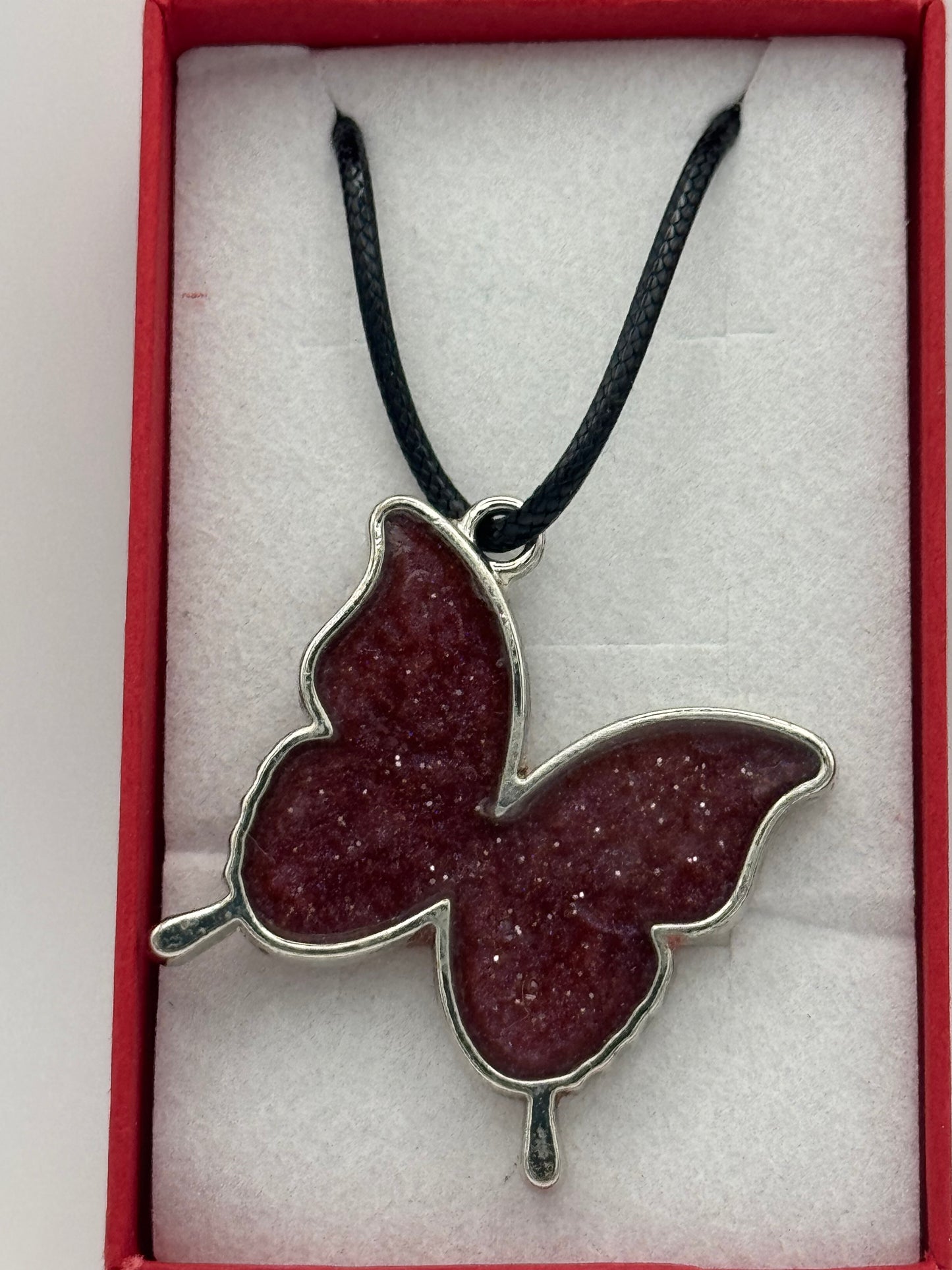 Red resin and metal butterfly necklace on black waxed chain