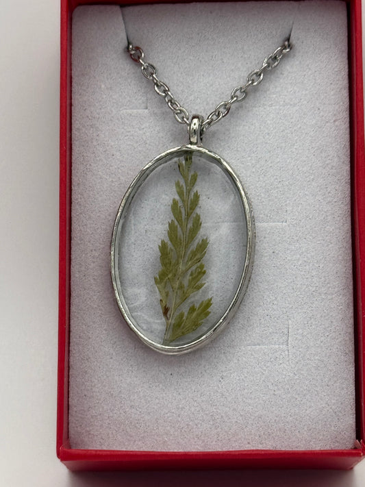 Necklace with flower encased in clear resin on a stainless steel chain